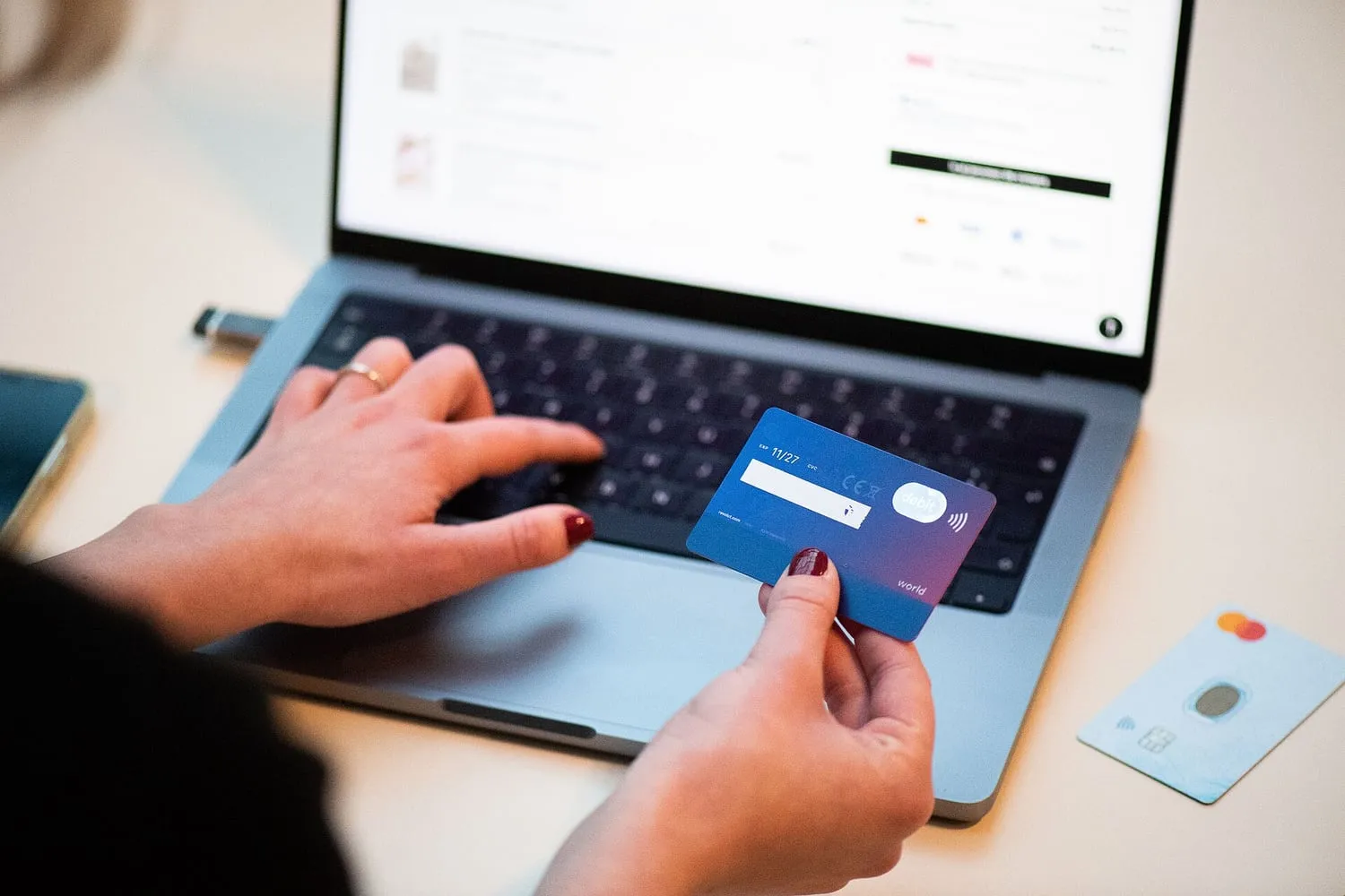 A person holding a bank card while shopping on a laptop